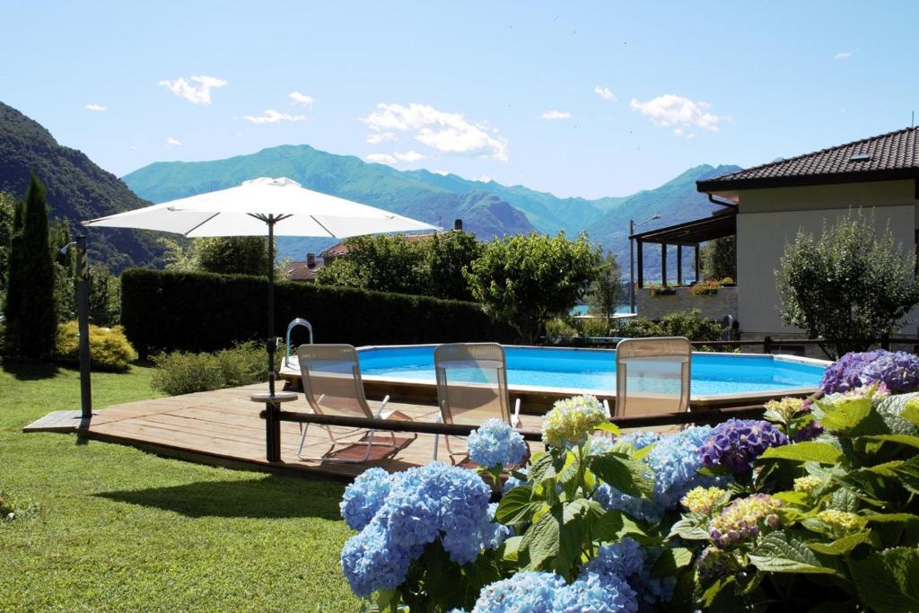 a pool with two chairs and an umbrella and flowers at Villa Tre Cariole in Colico