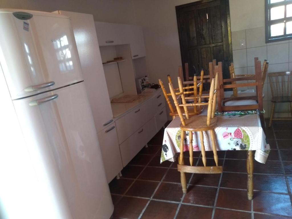 een keuken met een tafel en stoelen en een koelkast bij Casa Fávero Bairro Arco iris in Capão da Canoa