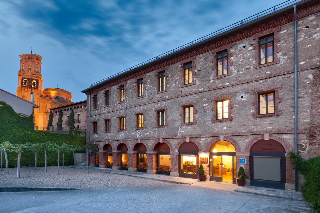 ein großes Backsteingebäude mit einem Uhrturm im Hintergrund in der Unterkunft Hospedería de Alesves in Villafranca