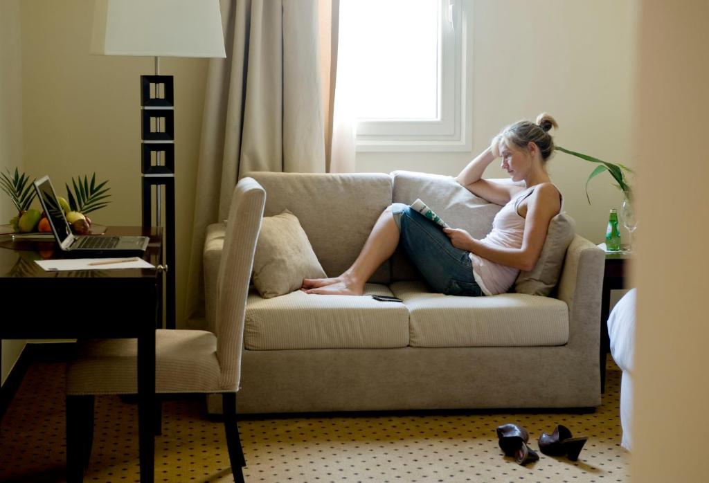 a woman sitting on a couch reading a book at Barceló Cairo Pyramids in Cairo