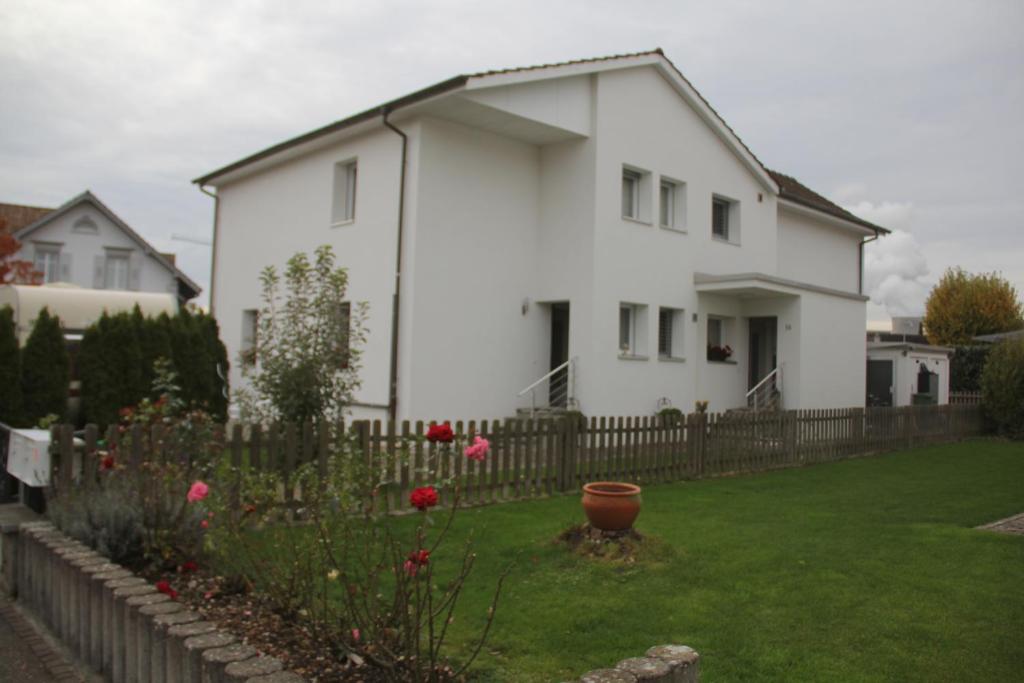 una casa blanca con una valla y un patio en Muhusin Apartments en Aarau
