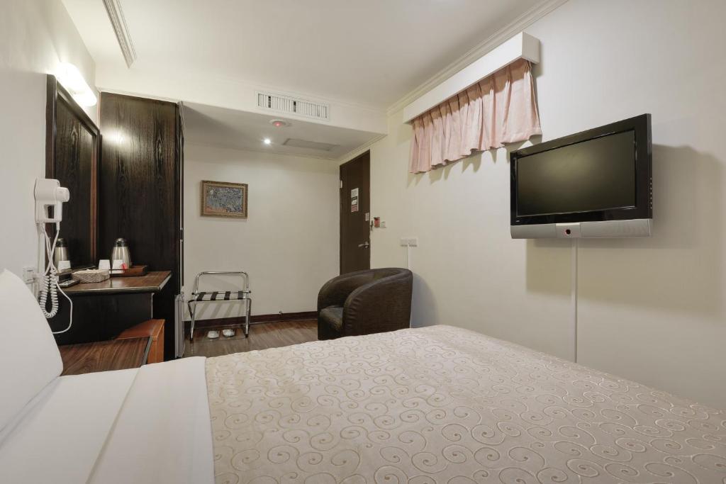 a hotel room with a bed and a flat screen tv at Kaja Hotel in Kaohsiung