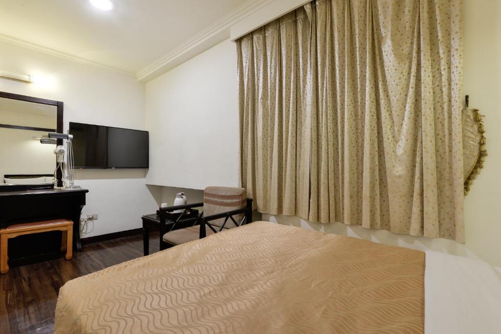 a hotel room with a bed and a desk at Kaja Hotel in Kaohsiung