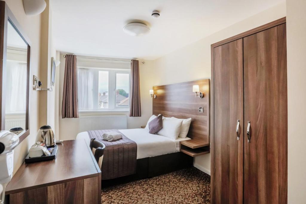 a bedroom with a bed and a dresser at Prince Regent Hotel Excel London in London