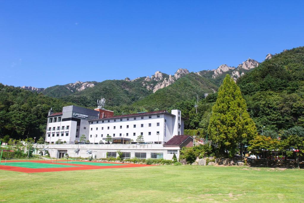 a large white building with a field in front of a mountain at Daedunsan Hotel in Wanju