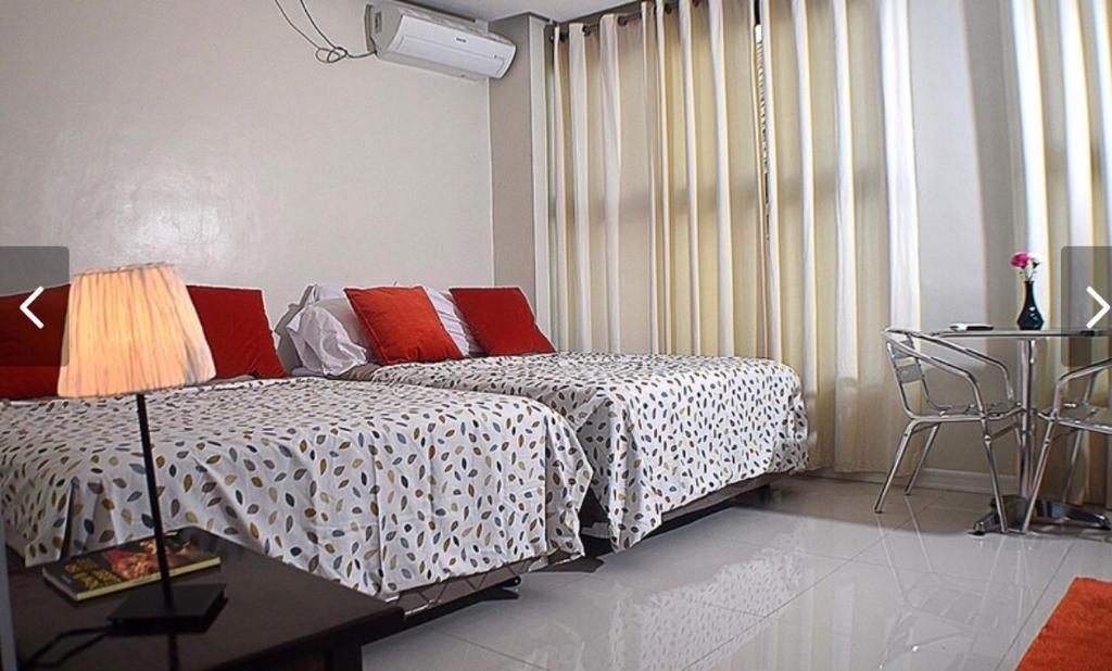 um quarto com uma cama, uma mesa e uma janela em The Guest House Laoag em Laoag