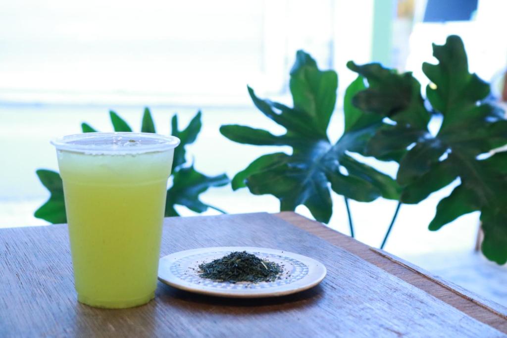 a glass of orange juice sitting on a table with a plate at Guest House MARUYA in Atami