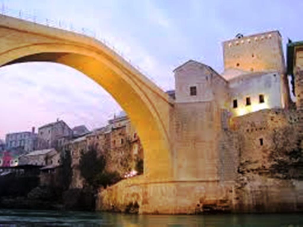 a bridge over a body of water with a building at Apartments Ajla in Mostar