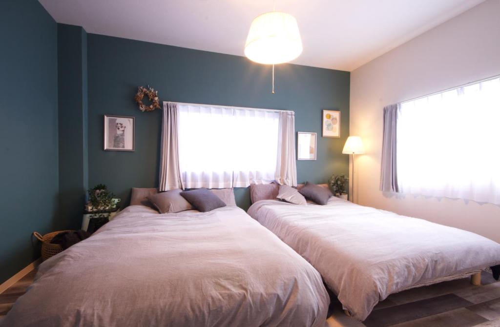 two beds in a bedroom with blue walls and a window at Guest House Re-worth Joshin1 3F in Nagoya