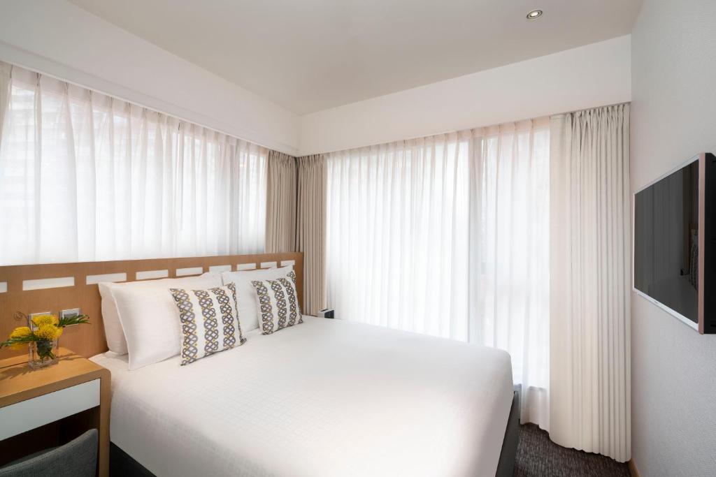 香港的住宿－香港莎瑪港島北服務式公寓，卧室配有白色的床和电视。