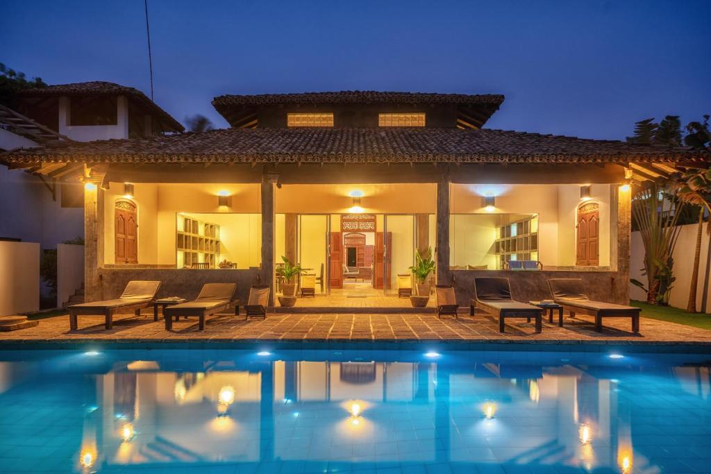 a villa with a swimming pool at night at Greenparrot-Villa in Ambalangoda