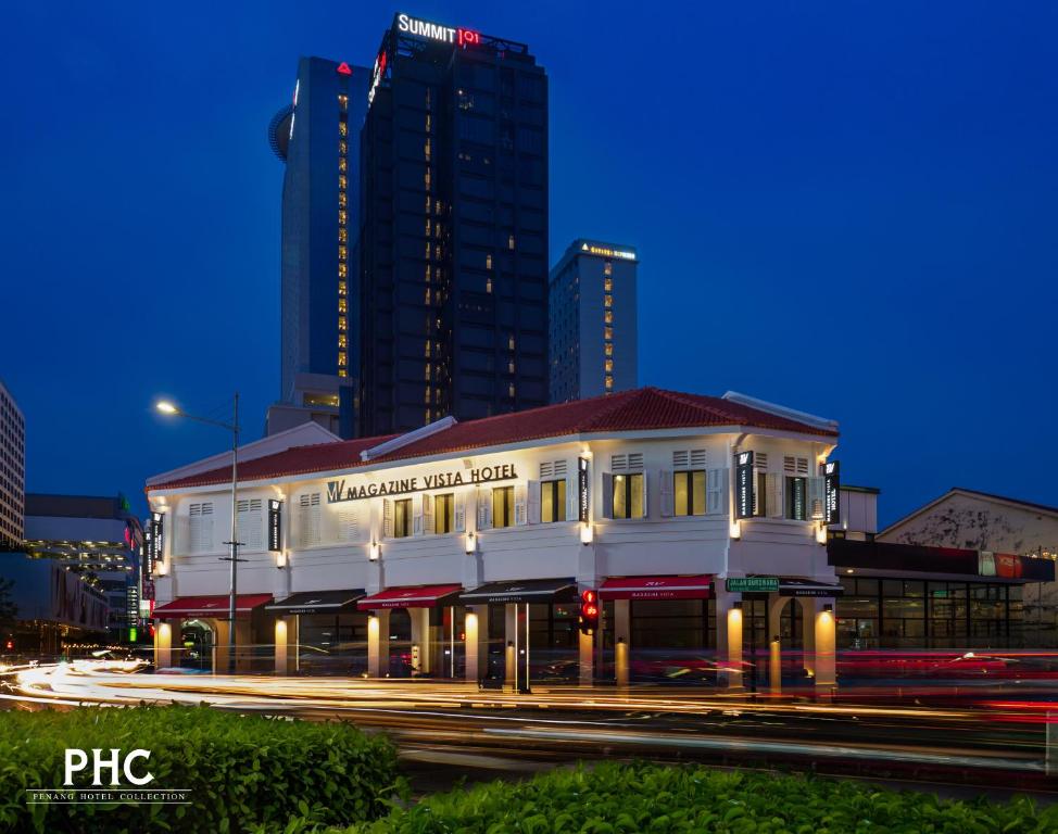 a white building in front of a tall building at Magazine Vista Hotel Managed by The Ascott Limited in George Town