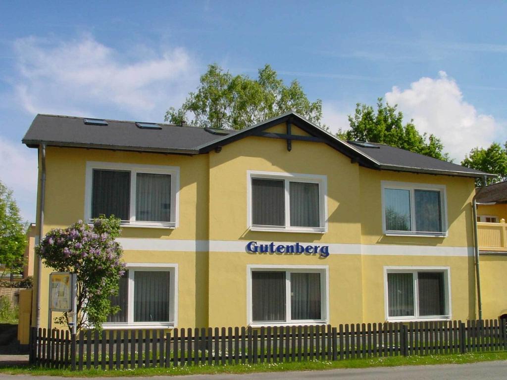 ein gelbes Haus mit schwarzem Dach in der Unterkunft Appartementhaus Gutenberg in Binz