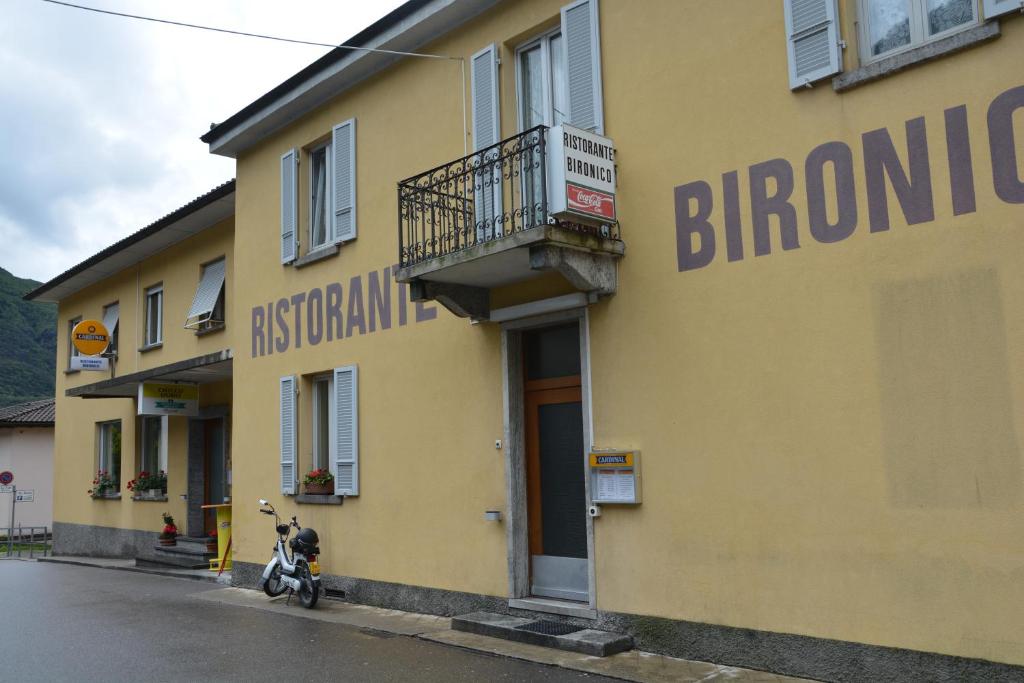 una motocicleta estacionada frente a un edificio amarillo en Ristorante Bironico, en Bironico