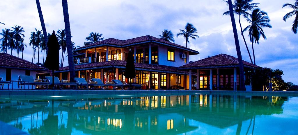 a house with a swimming pool and palm trees at Kottukal Beach House by Jetwing in Arugam Bay