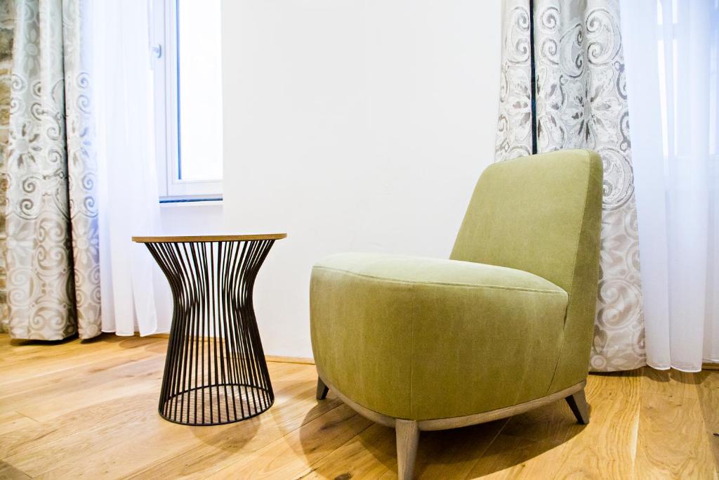 a green chair and a side table in a room at MEMENTO B&B Piran in Piran
