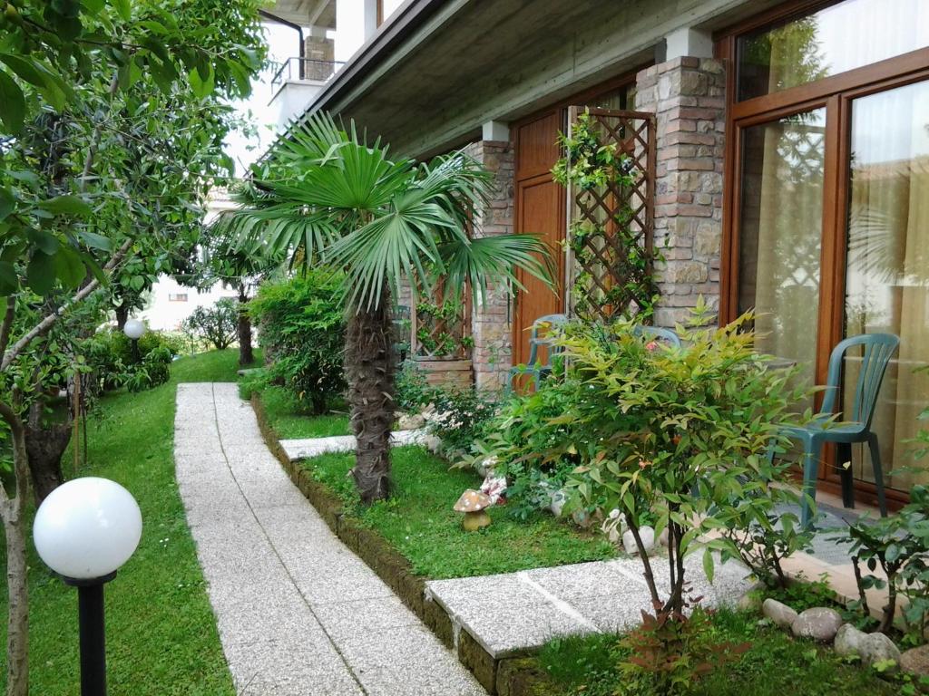 un jardín con una palmera y una casa en B&B Il Rondò Sirmione, en Sirmione