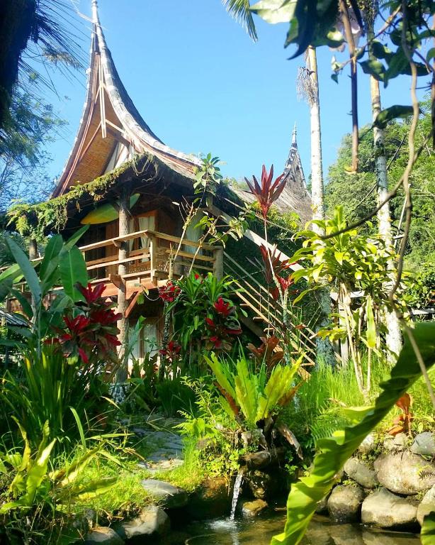 a resort with a pond in front of a house at SUMATRA ECORESORT in Bukittinggi