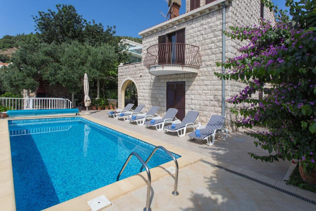 - une piscine avec des chaises longues à côté d'un bâtiment dans l'établissement Villa Ana Maria, à Zaton