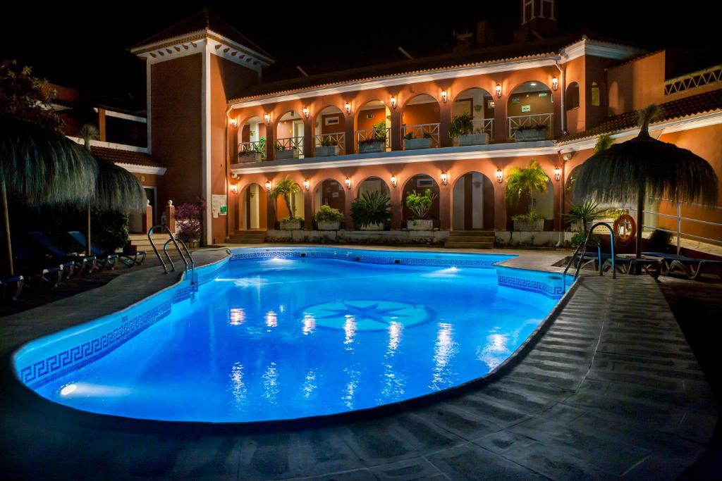 a swimming pool in front of a building at night at Los Arcos in Nerja