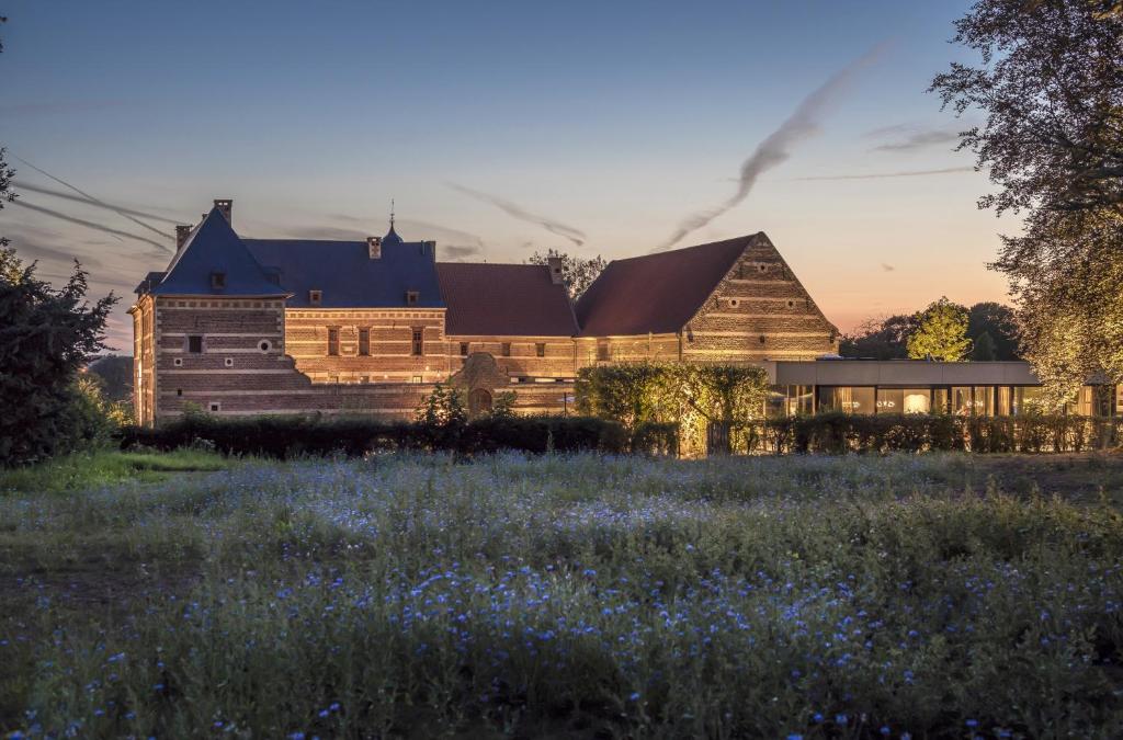 a large building with a field of flowers in front of it at Martin's Rentmeesterij in Bilzen