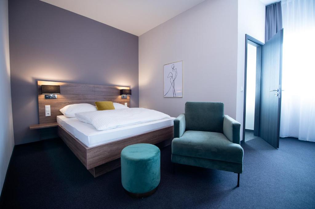a bedroom with a bed and a chair at V Boutique Hotel Böblingen in Böblingen