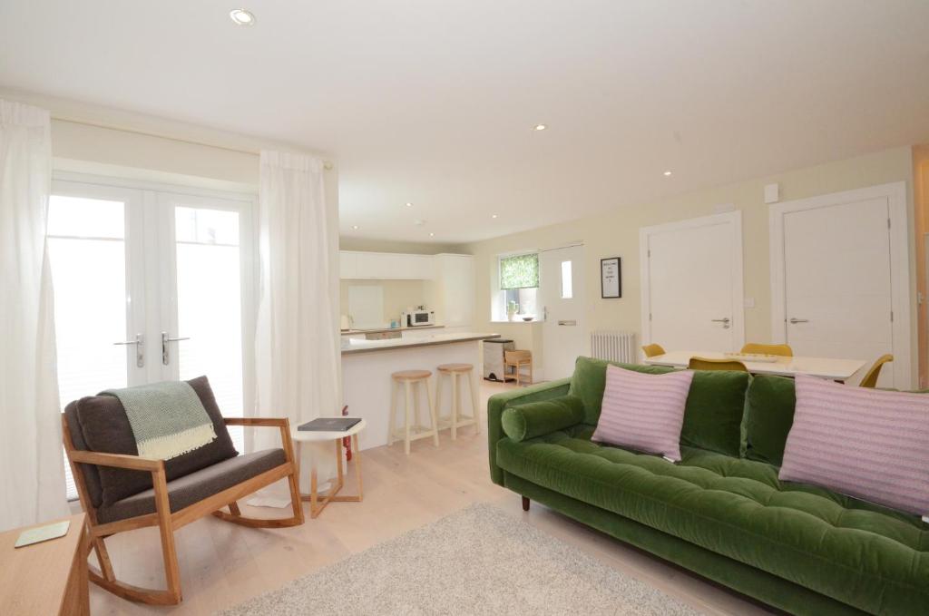 ヨークにあるThe Mews - 2 Bedroom Luxury, Spacious House With Free Parkingのリビングルーム(緑のソファ付)、キッチンが備わります。
