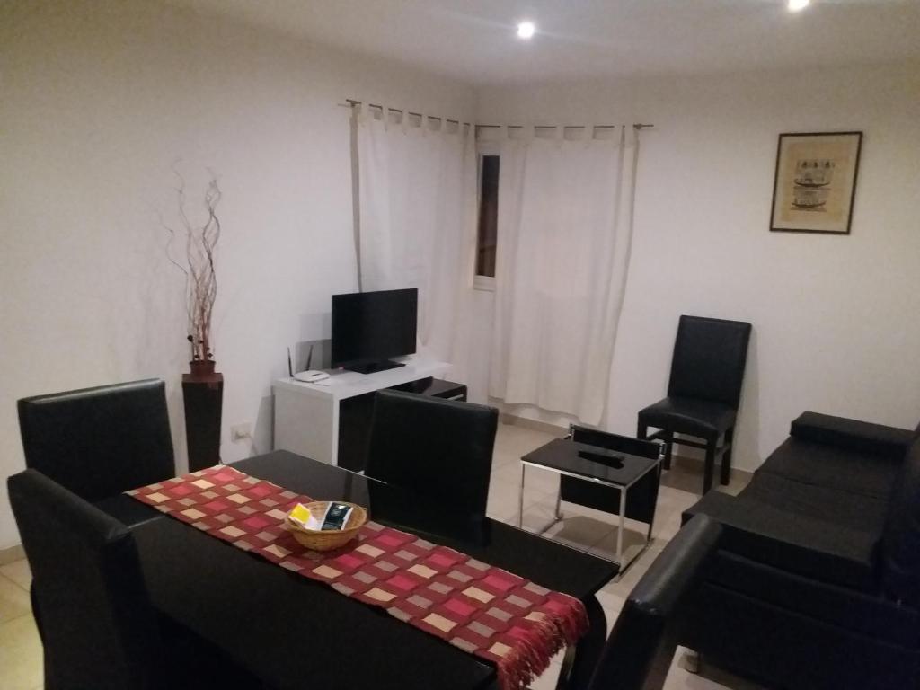 uma sala de estar com uma mesa e cadeiras e uma televisão em Departamento Amoblado 2 dormitorios em Rio Grande