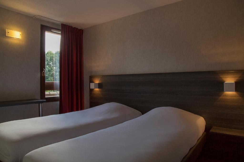 a hotel room with two beds and a window at The Originals City, Hôtel Amys, Tarbes Sud (Inter-Hotel) in Odos