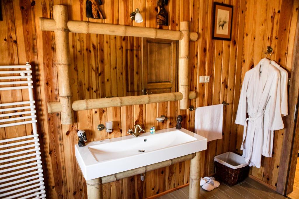uma casa de banho com um lavatório branco e paredes de madeira em Hunor Hotel és Étterem em Vásárosnamény