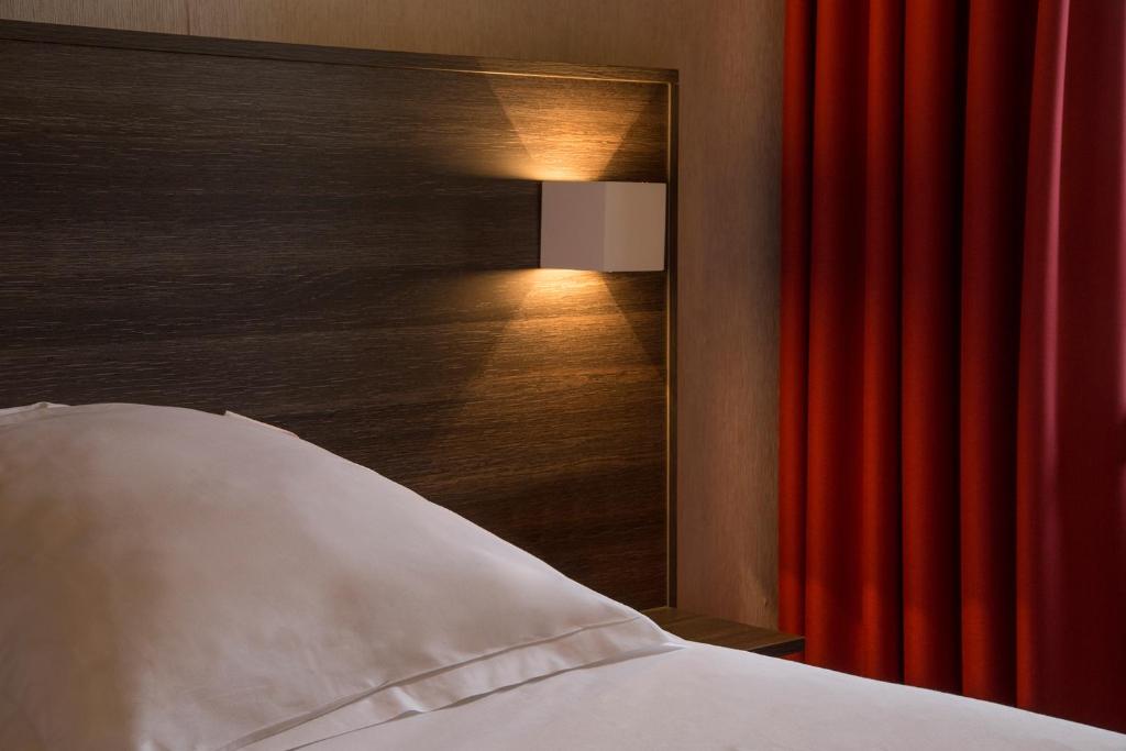 a bedroom with a bed and a red curtain at The Originals City, Hôtel Amys, Tarbes Sud (Inter-Hotel) in Odos