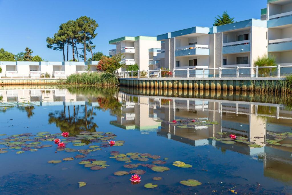 a river with lily pads in front of a building at Azureva Lacanau in Lacanau