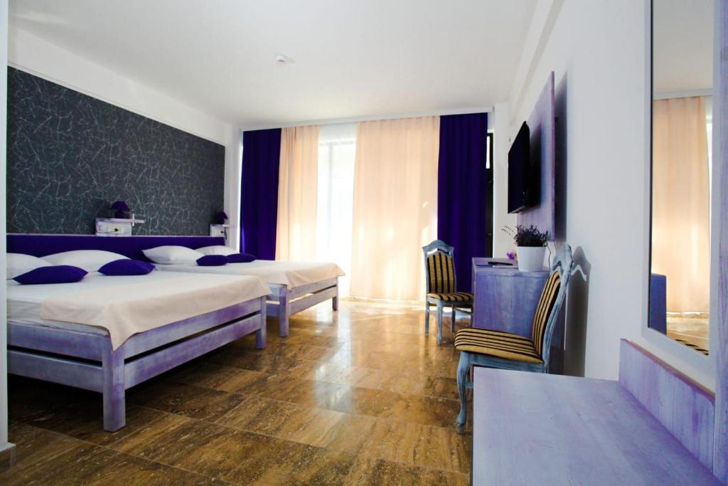 a bedroom with two beds and a table and chairs at Lavender Villa in Mamaia Sat/Năvodari
