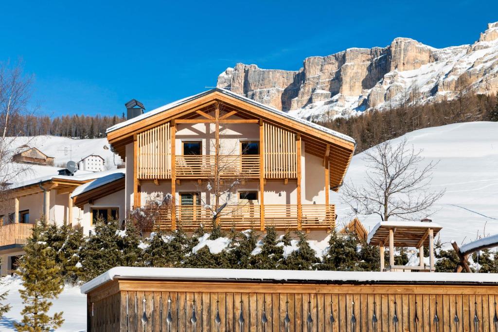 a house in the snow with a mountain in the background at Col Dala Vara in San Cassiano