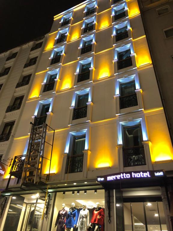 un edificio iluminado con una tienda delante en Meretto Hotel LALELİ, en Estambul