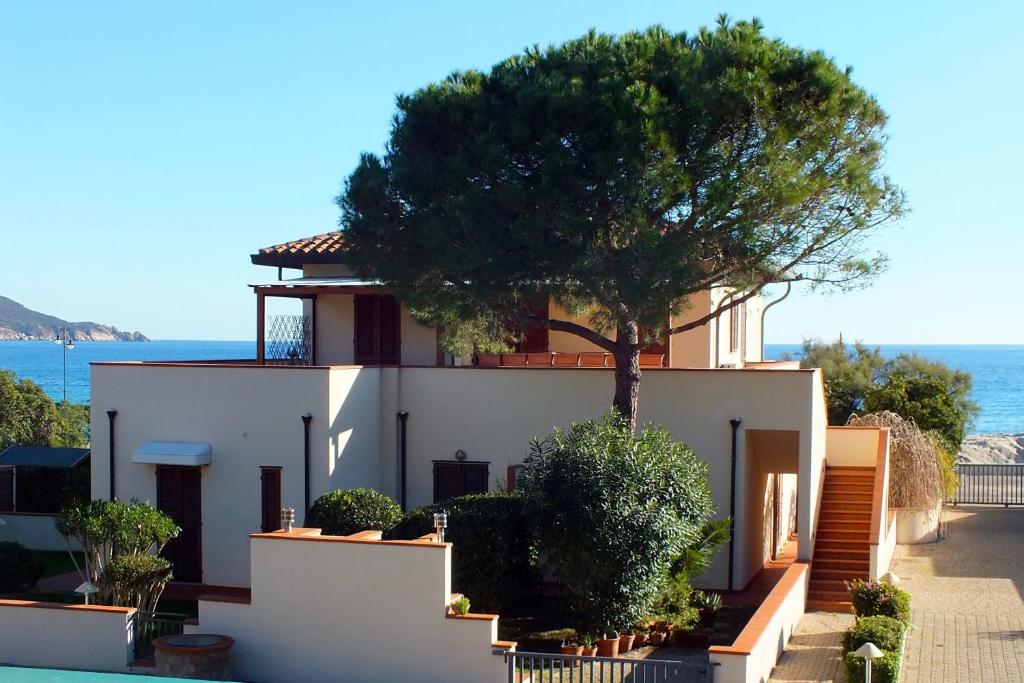a house with a tree on the side of it at Appartamento Il Sole in Marina di Campo