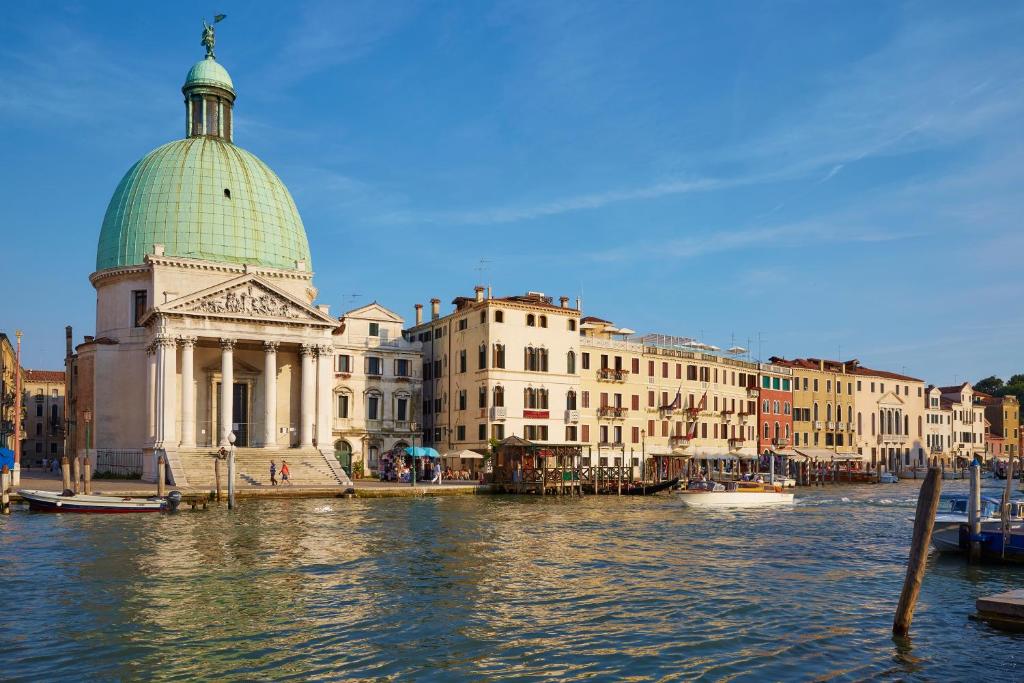 a building with a green dome next to the water at Hotel Antiche Figure in Venice