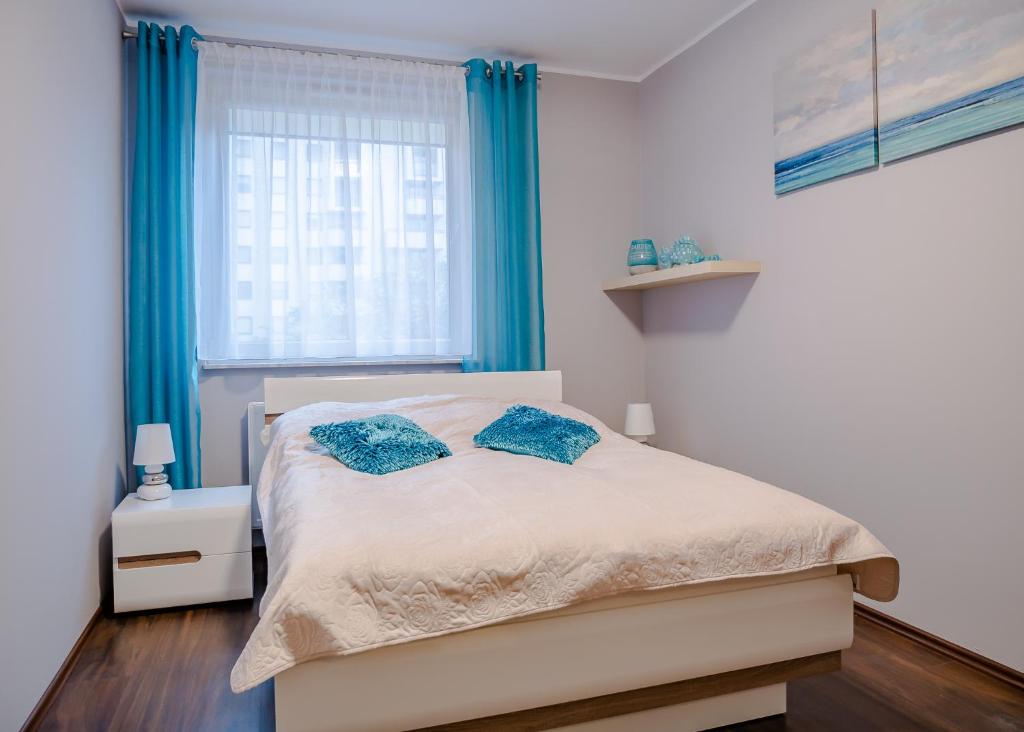 a bedroom with a bed and a window with blue curtains at Dream Bay Apartment in Gdańsk