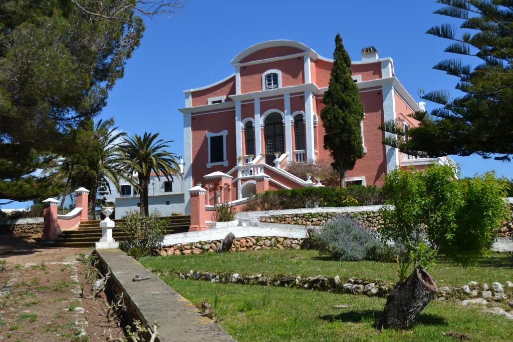 Agroturismo Son Triay في فيريريس: منزل وردي كبير أمامه شجرة