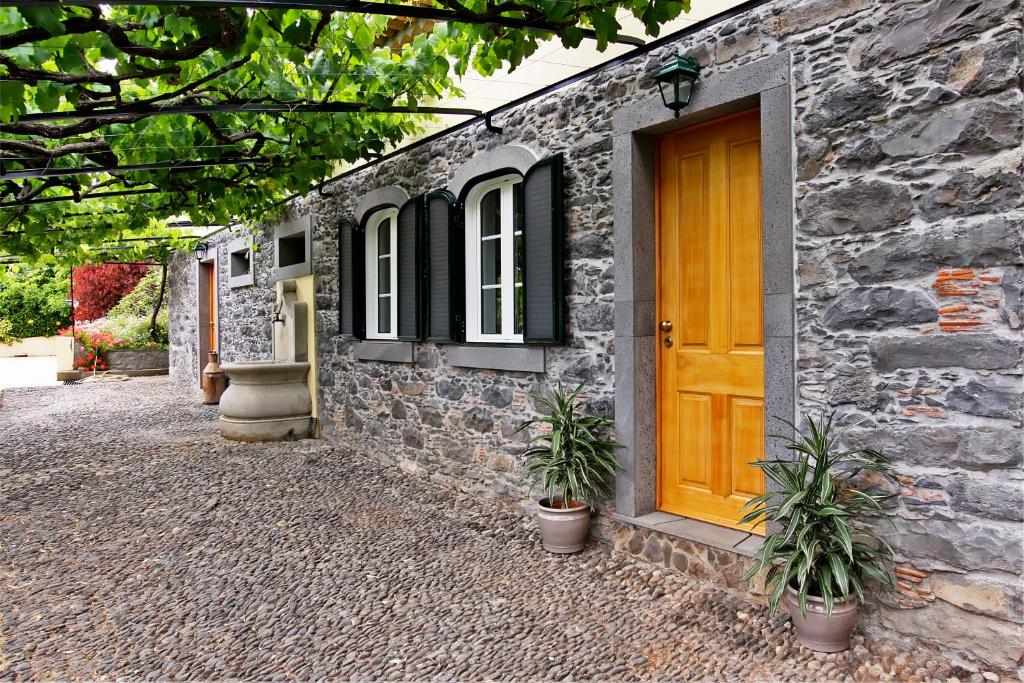 フンシャルにあるOurMadeira - Casa das Vinhas, charmingの黄色い扉と2本の植物があるレンガ造りの家
