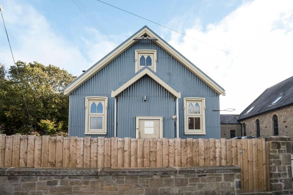 uma igreja azul atrás de uma cerca de madeira em The Iron Chapel em Ryton