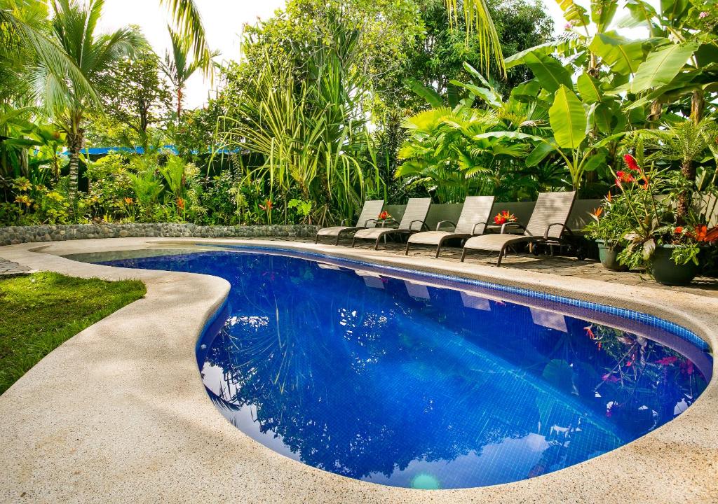a swimming pool in a yard with chairs and trees at Villas Oasis in Manuel Antonio