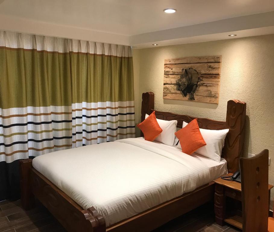 Progressive Park Hotel في نيروبي: غرفة نوم مع سرير كبير مع وسائد برتقالية