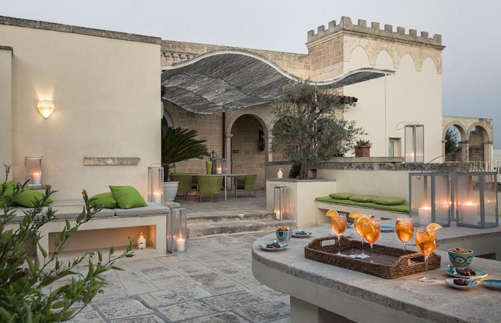 un patio con una mesa con copas de vino. en Don Totu - Dimora Storica, en San Cassiano