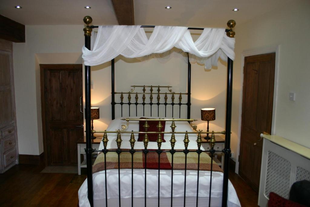 1 dormitorio con cama negra con dosel y cortinas blancas en Cadleigh Manor, en Ivybridge