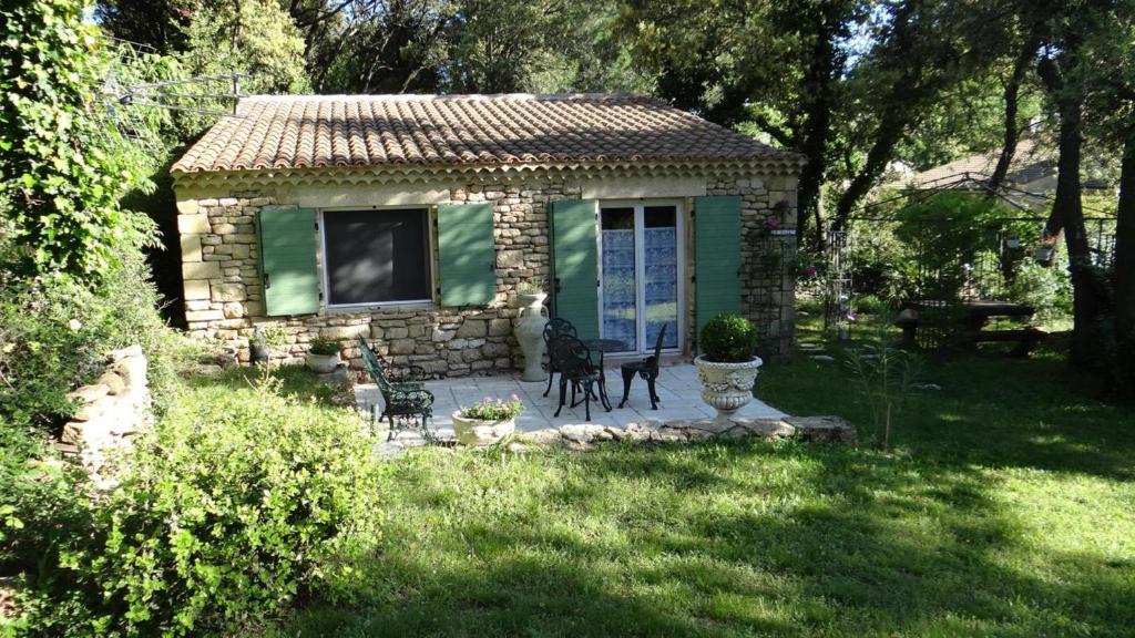a small stone house with a bench in a yard at Le Mazet in Remoulins