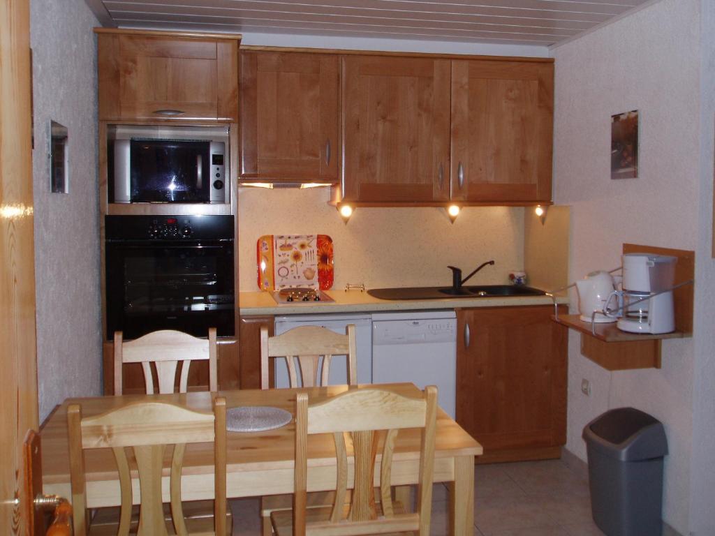 een keuken met houten kasten en een tafel en stoelen bij L'ancolie in Orelle
