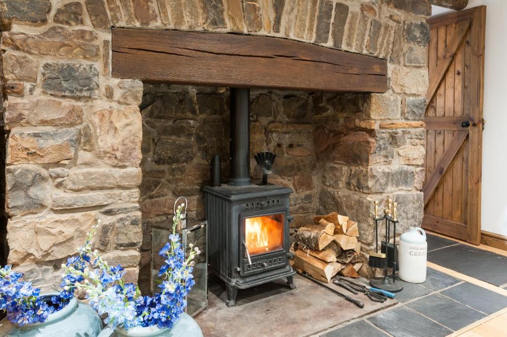 a stone fireplace in a room with a stove at Bryn-Y-Groes Cottage in Ystradgynlais