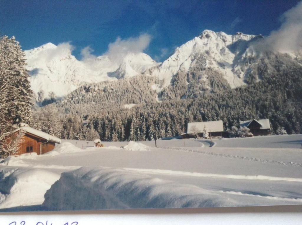 a snow covered mountain range with a house and a waterfall at Haus Elsa in Ramsau am Dachstein
