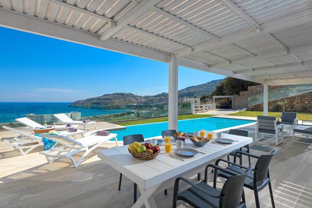 a dining room with a table and chairs and a pool at Villa Gaia in Líndos
